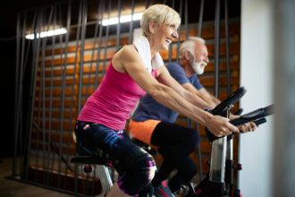 Happy senior people doing indoor biking in a fitness club