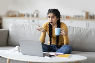 Unexpected News. Shocked indian woman looking at laptop with disbelief